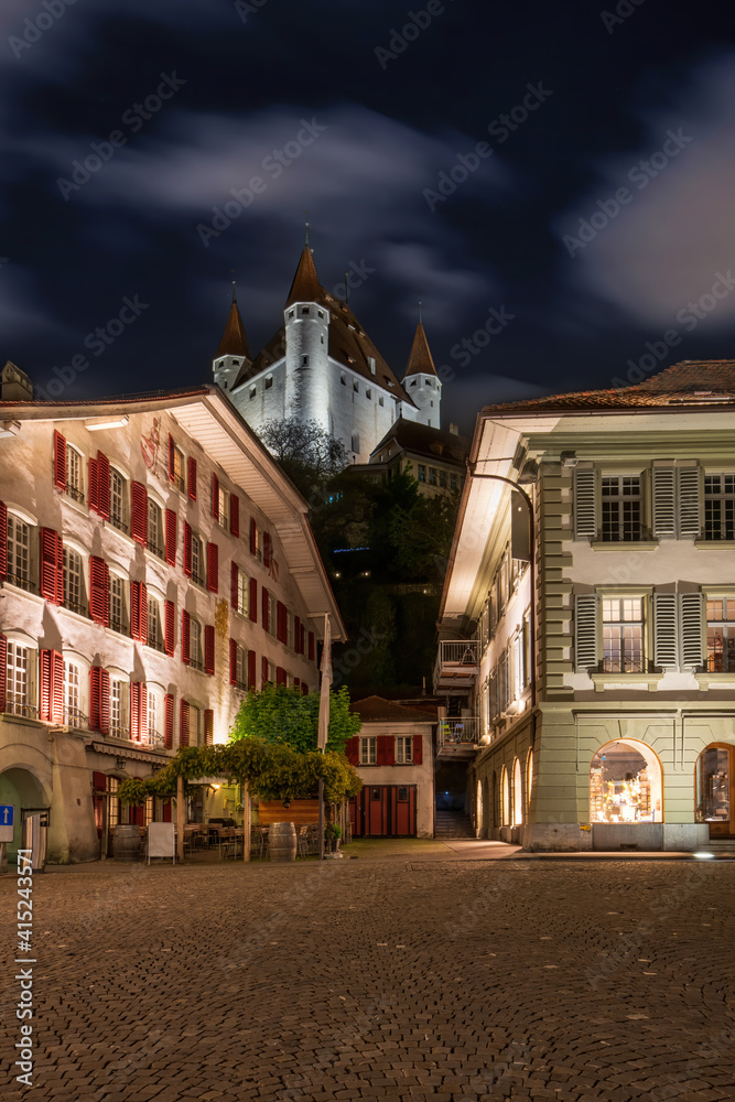 Obraz premium Picturesque nightscape of illuminated buildings and castle of Thun, Switzerland under starry sky