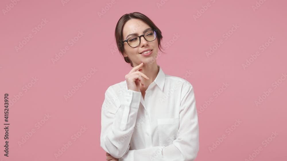Smiling pensive young business woman 20s years old in white shirt glasses looking around think dream put hand prop up on chin isolated on pink background in studio. Achievement career wealth concept Smiling pensive young business woman 20s years old in white shirt glasses looking around think dream put hand prop up on chin isolated on pink background in studio. Achievement career wealth concept