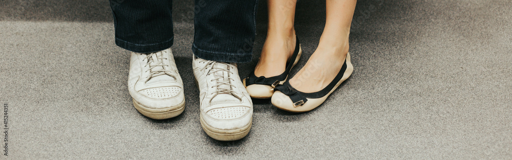 Closeup of man and woman legs in outdoor shoes together. Couple dating sitting together. Love and romance. Romantic dating. Details and body part. Web banner header.