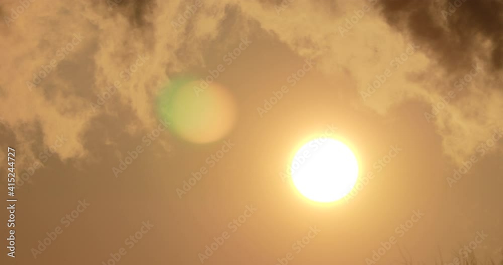 Clouds float against the sun at sunset, the plane flies from left to right