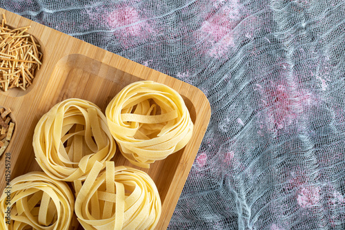 Assortment of uncooked pasta on wooden plate photo