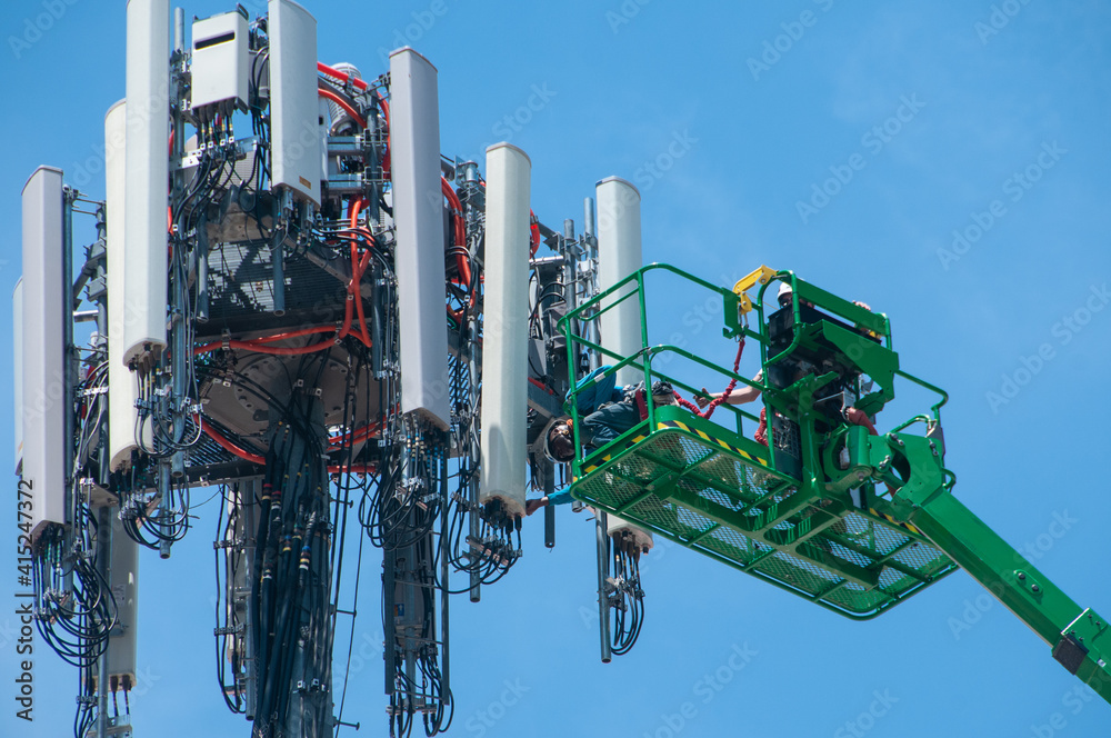 Fototapeta premium A work crew performs maintenance on a cell phone transmission tower. 