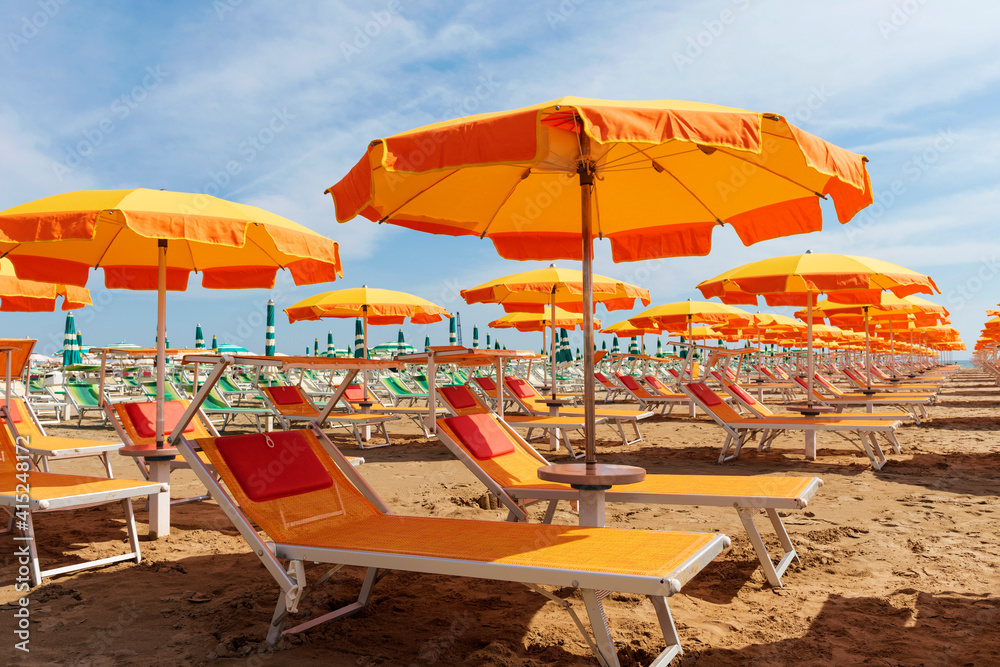 Bright orange umbrellas and sun loungers on the beach in Rimini, Italy. 