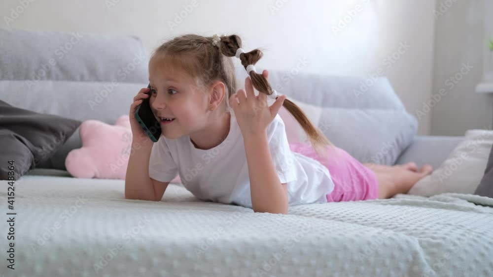 A 7-8 year old girl is lying on a gray sofa and talking on the phone.
The child communicates via a smartphone with friends. A 7-8 year old girl is lying on a gray sofa and talking on the phone.
The child communicates via a smartphone with friends.