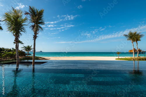 Panoramic pool with palm trees on a sandy beach in Dubai