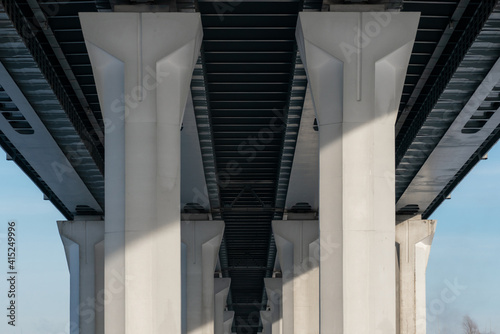 Bridge bottom view in winter. Metal structures and columns against the sky.