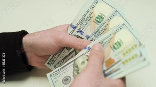Hands are counting money. One hundred US dollar bills.
