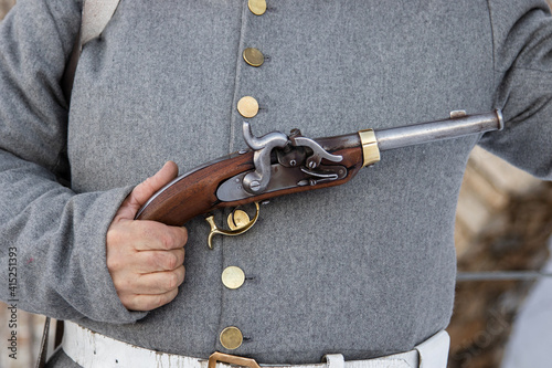 Male hands are holding a firearm - a pistol from the era of the Napoleonic Wars. Historical weapons, antiques. Short-barreled weapon. 