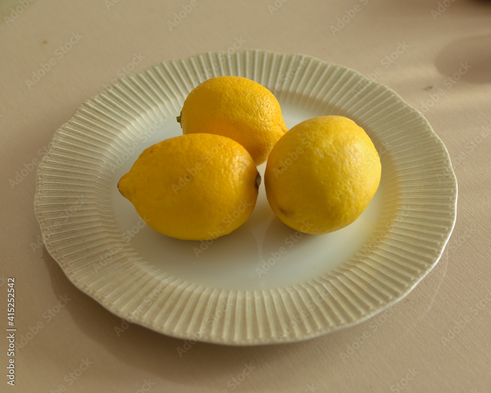 Three lemons on a plate. source of vitamin C.
