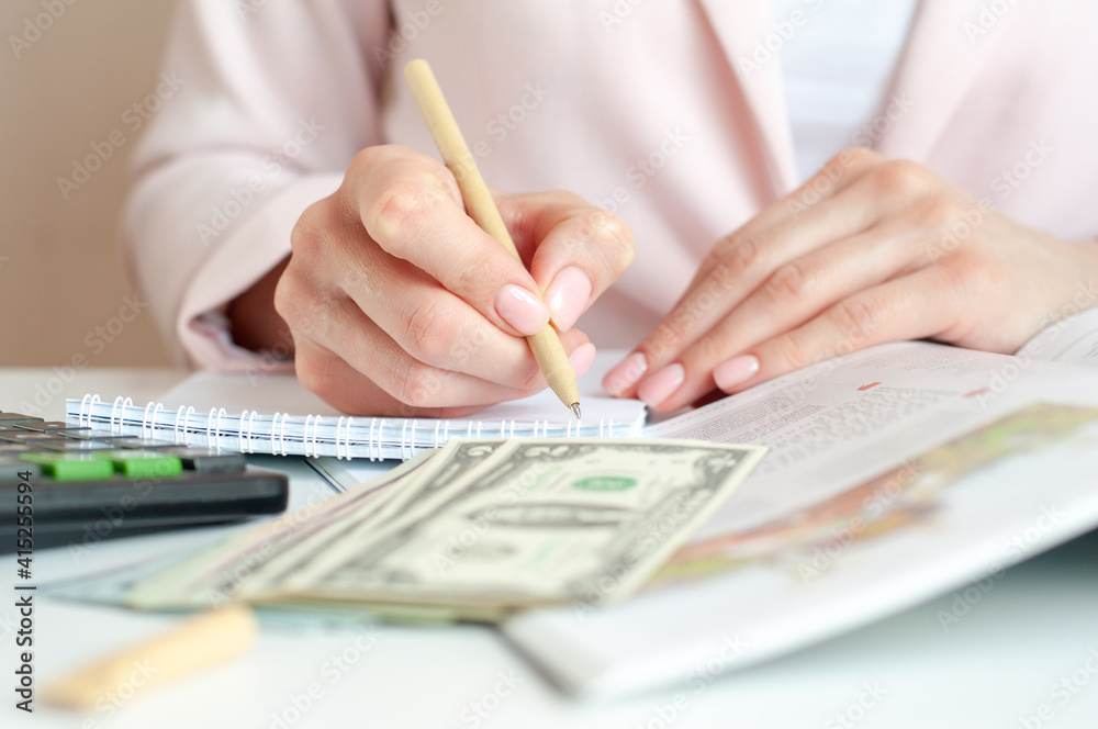 close up of woman hands with calculator counting and taking notes to notebook close up of woman hands with calculator counting and taking notes to notebook