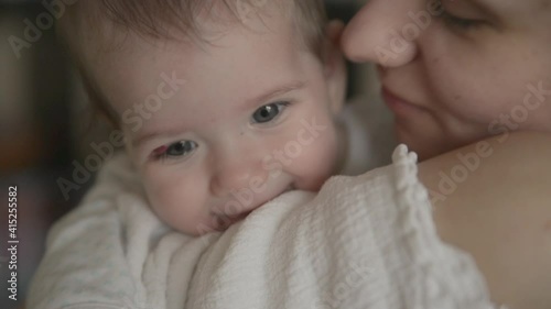 Mother kisses and hugs a 6 months old baby, maternal care and love. Close-up shot.