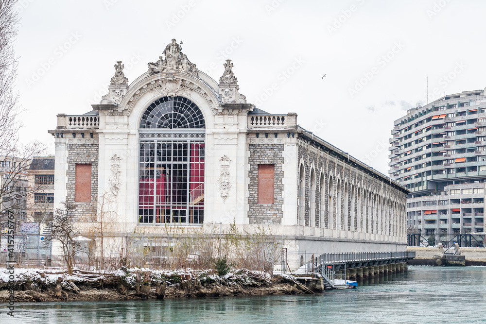 Fototapeta premium Facade of the former hydro power plant building on Geneva lake after snow blizzard. February 13, 2021.