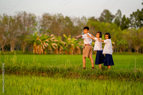 Children of student and wearing uniform playing in rice field on morning of countryside