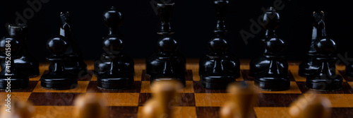 Black chess pieces against white chess pieces on a chessboard