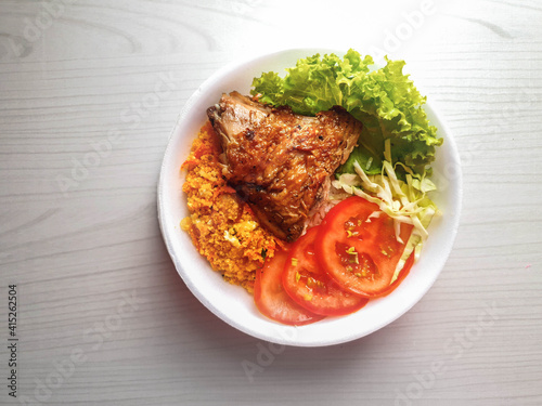 lunch box with roasted chicken, farofa, salad with tomato, cabbage and lettuce and rice in white styrofoam pot and background with space for text and 