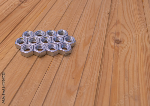Metal shine nuts on wooden background. Copy Space