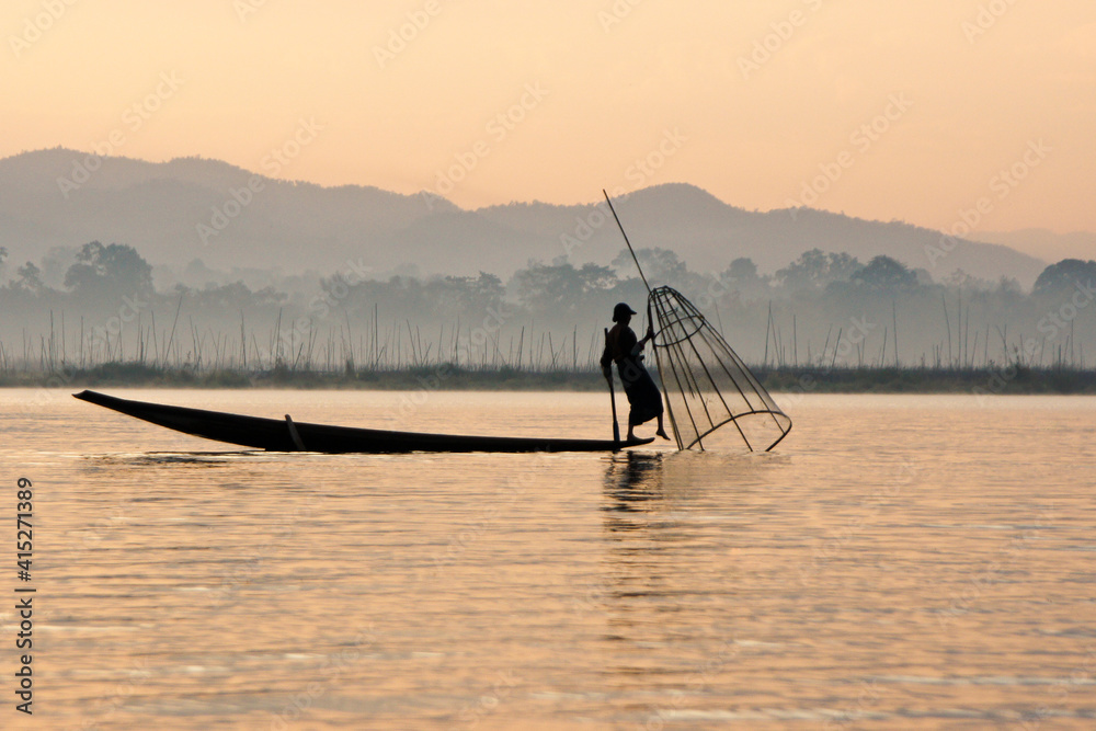 Intha leg-rowing fisherman with basket net near floating gardens on Inle Lake at sunrise, Myanmar (Burma)