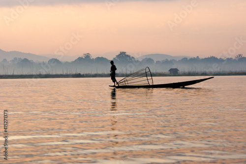 Intha leg-rowing fisherman with basket net near floating gardens on Inle Lake at sunrise, Myanmar (Burma)