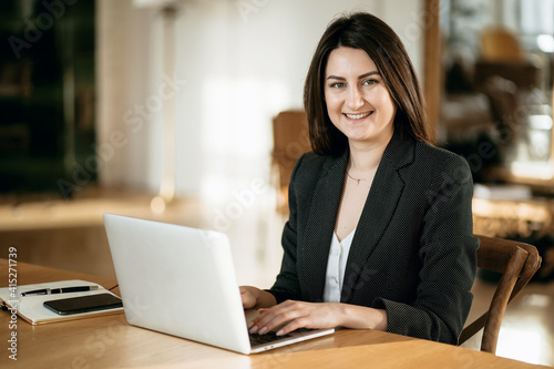 A female Manager Works on a Laptop in a Modern office. the 5G connection. Sitting in a Chair Typing a Message to Colleagues on a new project. She is passionate about her work.
