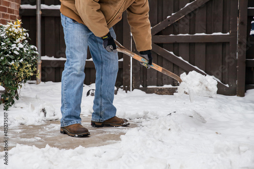 Photography Closeup of person with shovel clearing snow from sidewalk