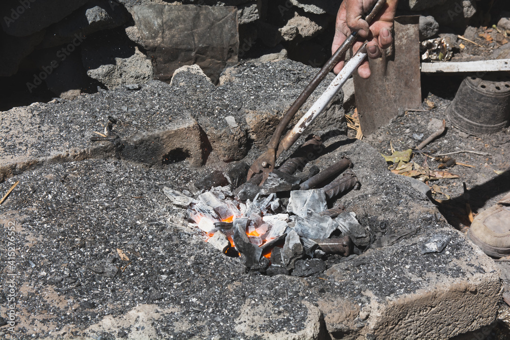 Obraz premium Forge bits of metal over hot embers to create chisels for stone crafts. 