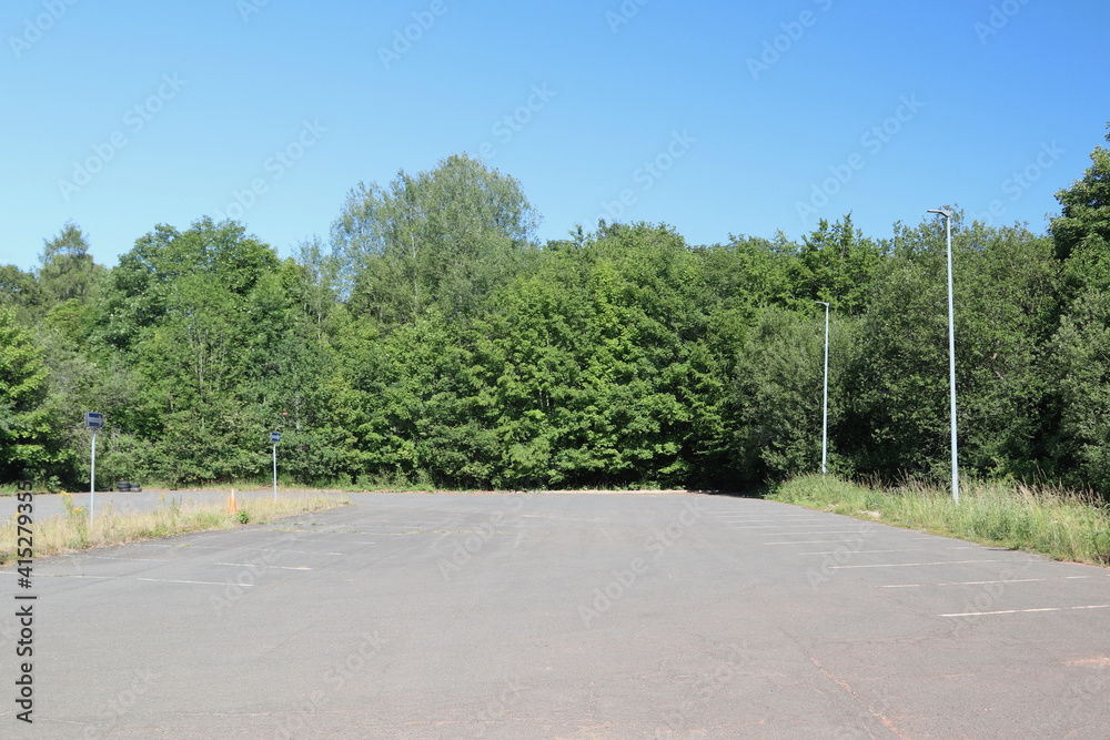 A large parking lot with green trees in the background
