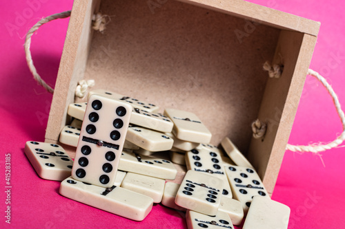 Old fashioned dirty domino on a box with pink solid backround
