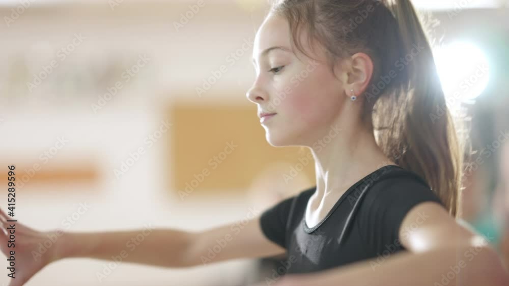 Concentrated girl rehearsing ballet dance with help of teacher in dance studio. Focused skilled Caucasian children studying classical dancing indoors. Professional teaching kids. Art and skill concept Concentrated girl rehearsing ballet dance with help of teacher in dance studio. Focused skilled Caucasian children studying classical dancing indoors. Professional teaching kids. Art and skill concept