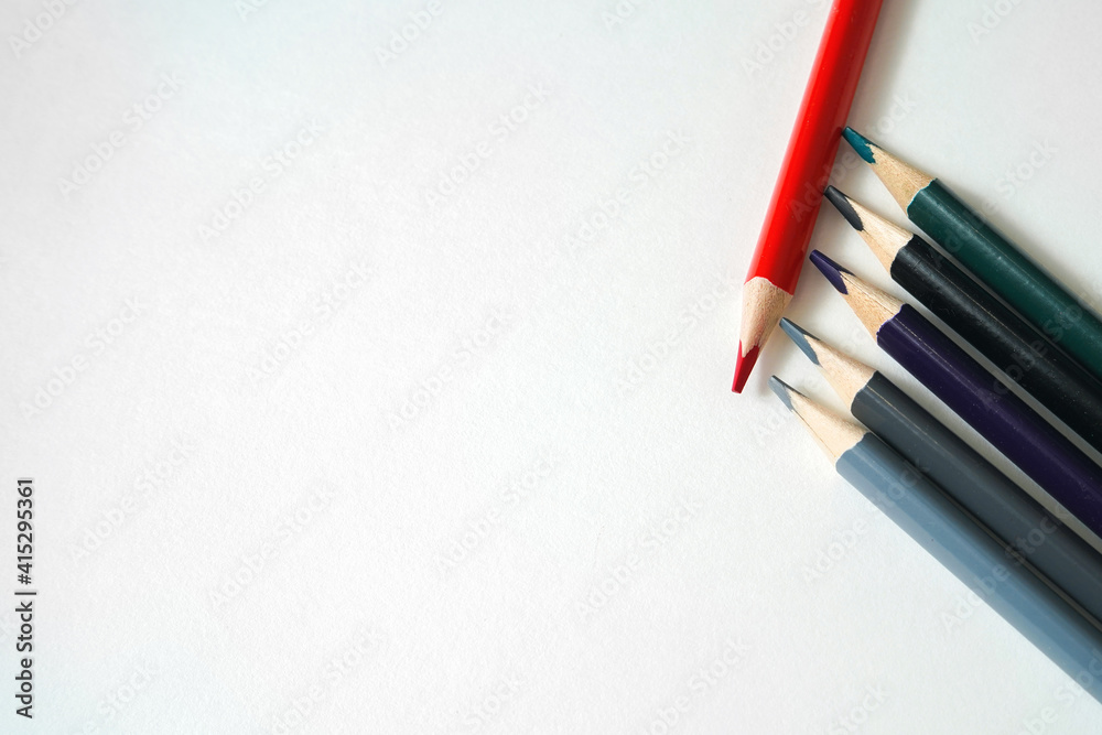 Bright red pencil on a background of dark pencils. Color highlight accents. Red versus gray. Colored pencils for drawing on a light background Bright red pencil on a background of dark pencils. Color highlight accents. Red versus gray. Colored pencils for drawing on a light background