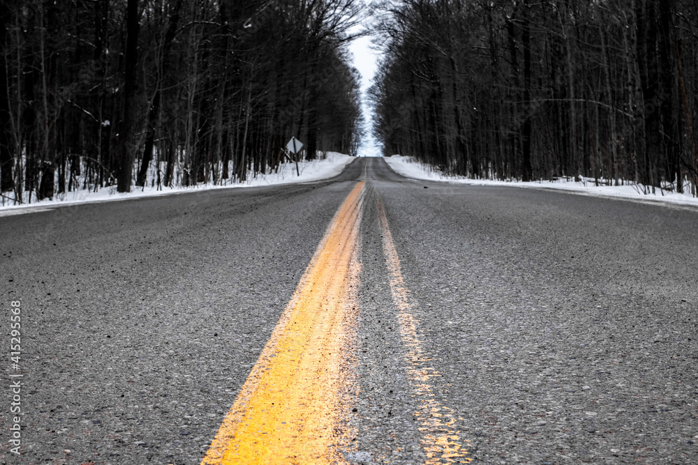 Closeup of the yellow line on an asphalt paved road in Middlesex County, on a gray Canadian winter day in 2021. Closeup of the yellow line on an asphalt paved road in Middlesex County, on a gray Canadian winter day in 2021.