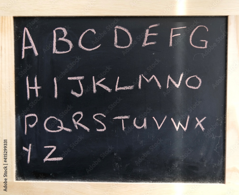 Obraz premium alphabet written on black chalkboard with pink chalk.