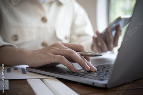 Financial businesswomen use laptop and smart phone to analyze marketing strategies and real estate data to reduce company taxes for their customers, Accounting and Tax concept.