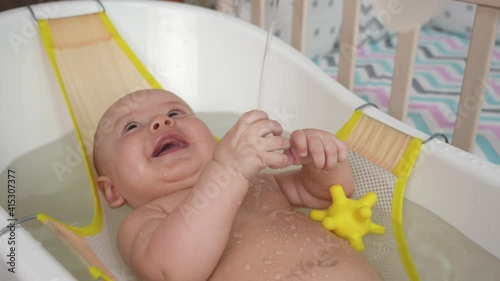 Mom pours water on the baby in the bathroom