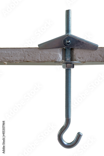 Metal folding spring anchor with hook mounted and screwed into a pre-drilled hole in a sheet of moisture-proof drywall, a view of a section of drywall, isolated on a white background.