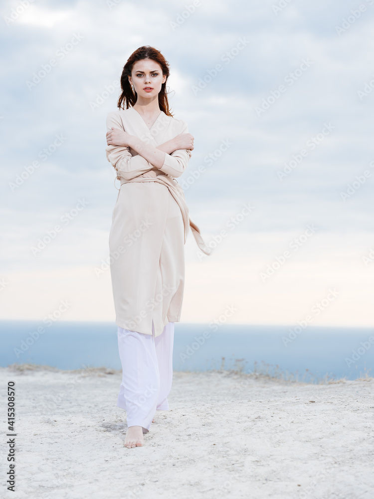 woman in light trousers and a sweater travels in the mountains on nature ocean in the background woman in light trousers and a sweater travels in the mountains on nature ocean in the background