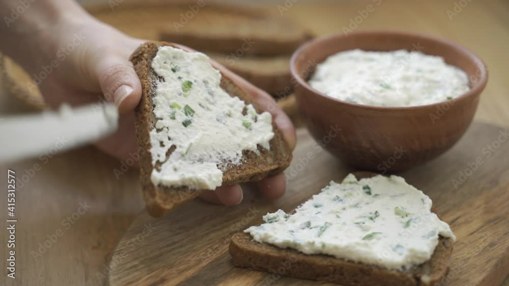 Spreading cream cheese with scallions on bread. Spreading cream cheese with scallions on bread.