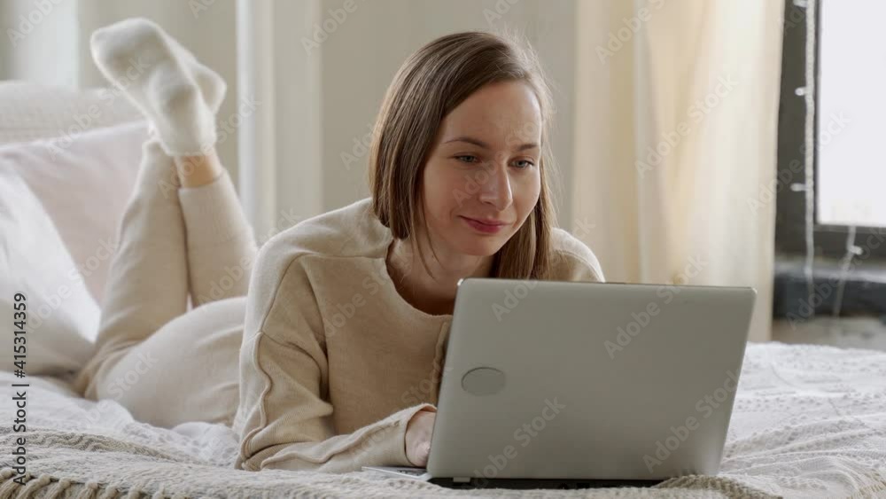 Relaxed brunette young woman using laptop in bed at home Relaxed brunette young woman using laptop in bed at home