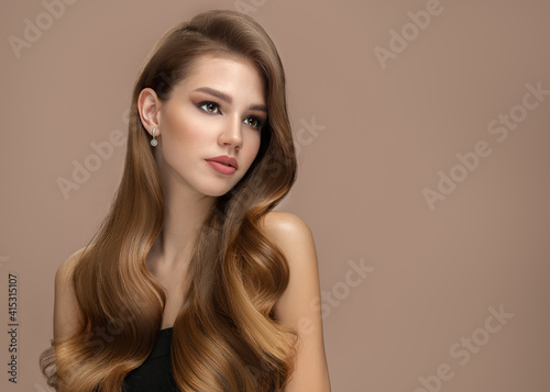 Long beautiful wavy hair. Portrait of a woman on a brown background with shiny hair. copycpase