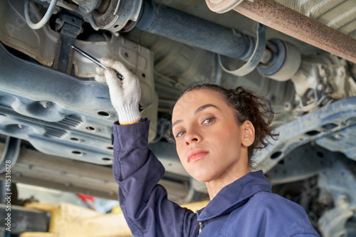 Female engineer fix or check under car with hydraulic lift in car service garage
