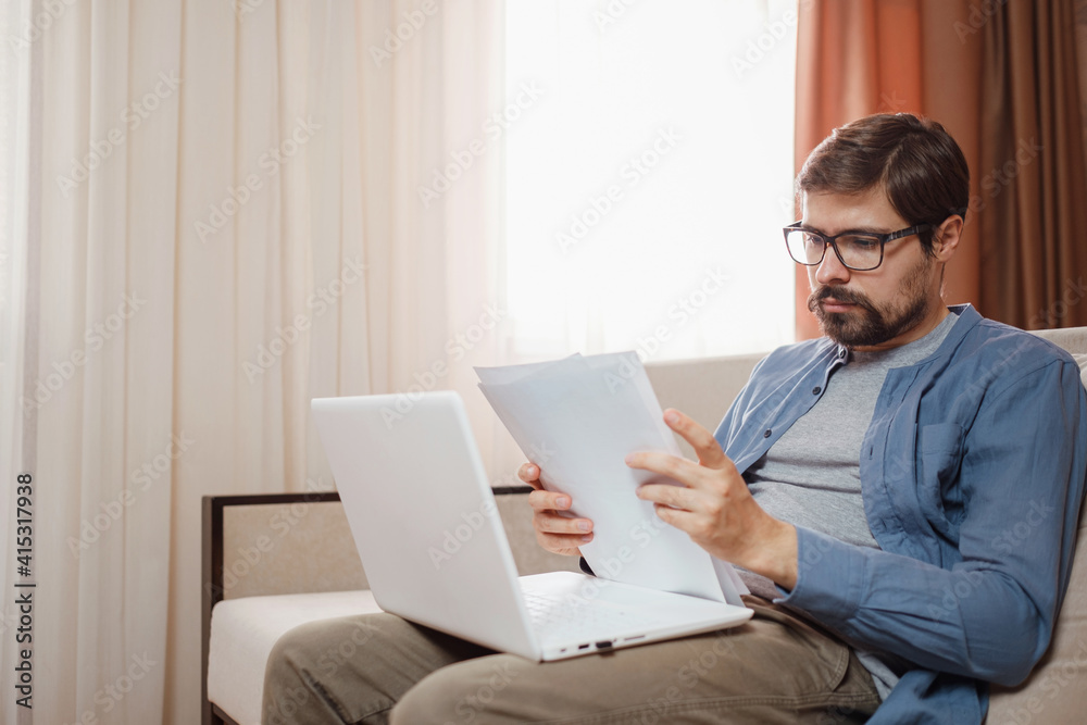 Entrepreneur works with a laptop and keeps a document in a home office Entrepreneur works with a laptop and keeps a document in a home office