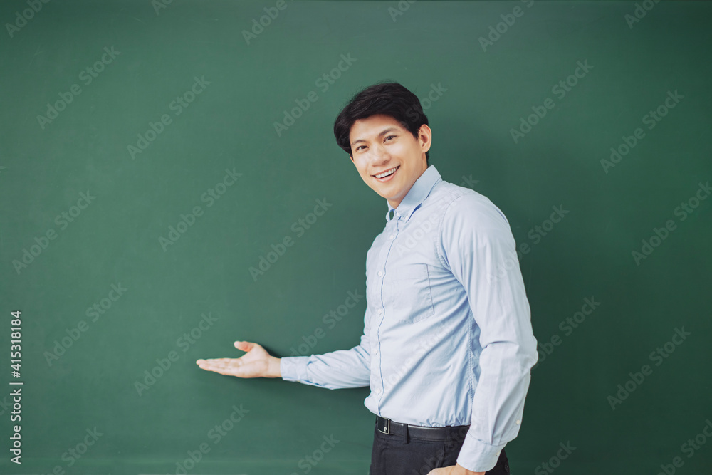 young smiling teacher standing in front of chalkboard