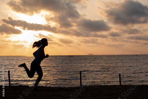  Silhouette woman running on the beach has to background the sunrise. New life for new year concept