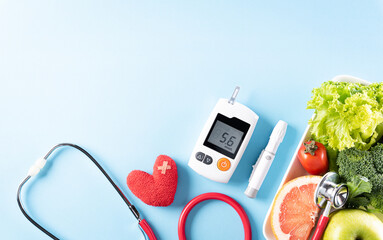 Top view of healthy food in plate with stethoscope and red heart for cholesterol diet and diabetes control on pastel blue background. World health day and medical concept.