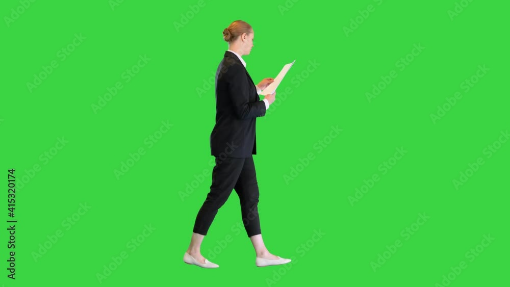 Young business woman looking through documents while walking on a Green Screen, Chroma Key. Young business woman looking through documents while walking on a Green Screen, Chroma Key.