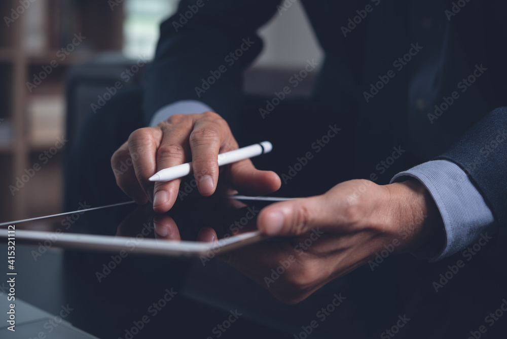 Businessman hand holding touchscreen pen working on digital tablet in office