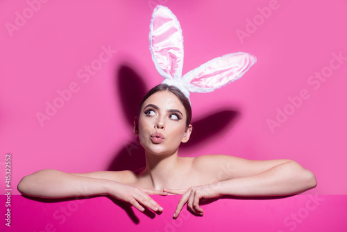 Easter young woman studio wearing bunny ears. curious isolated on pink. photo