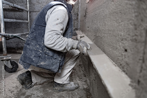 Real construction worker working on a wall inside the new house.