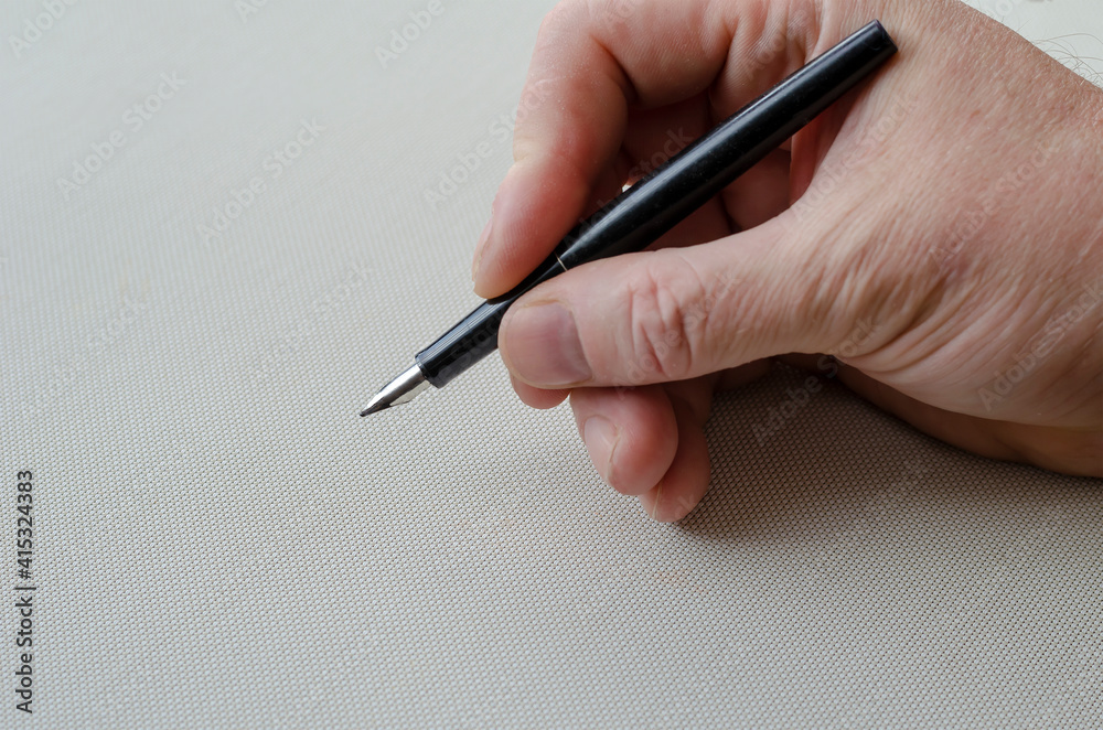 A man right-hand holds a fountain pen over a white table. A man right-hand holds a fountain pen over a white table.