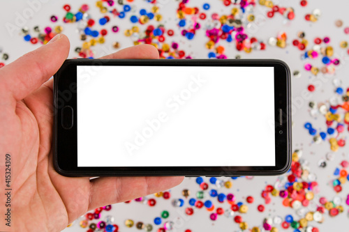 mobile phone with white screen on festive background in hand