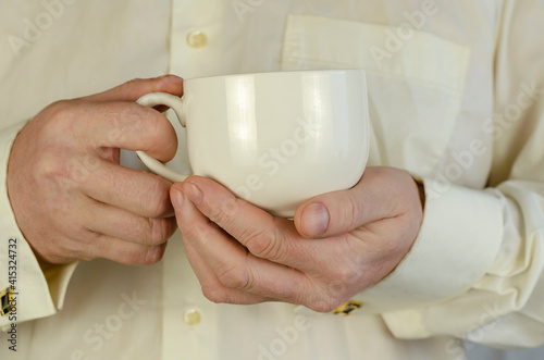 Adult Man is holding a large white mug.